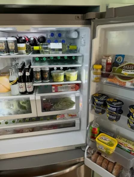 An open fridge stocked with drinks, fresh produce and groceries