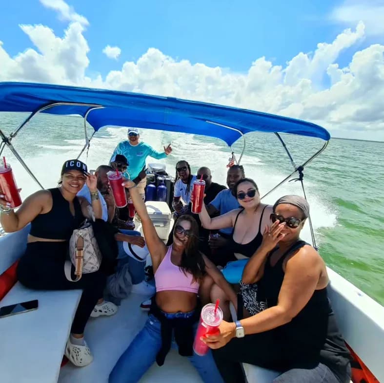 A group of smiling guests on a private boat speeding across turquoise water