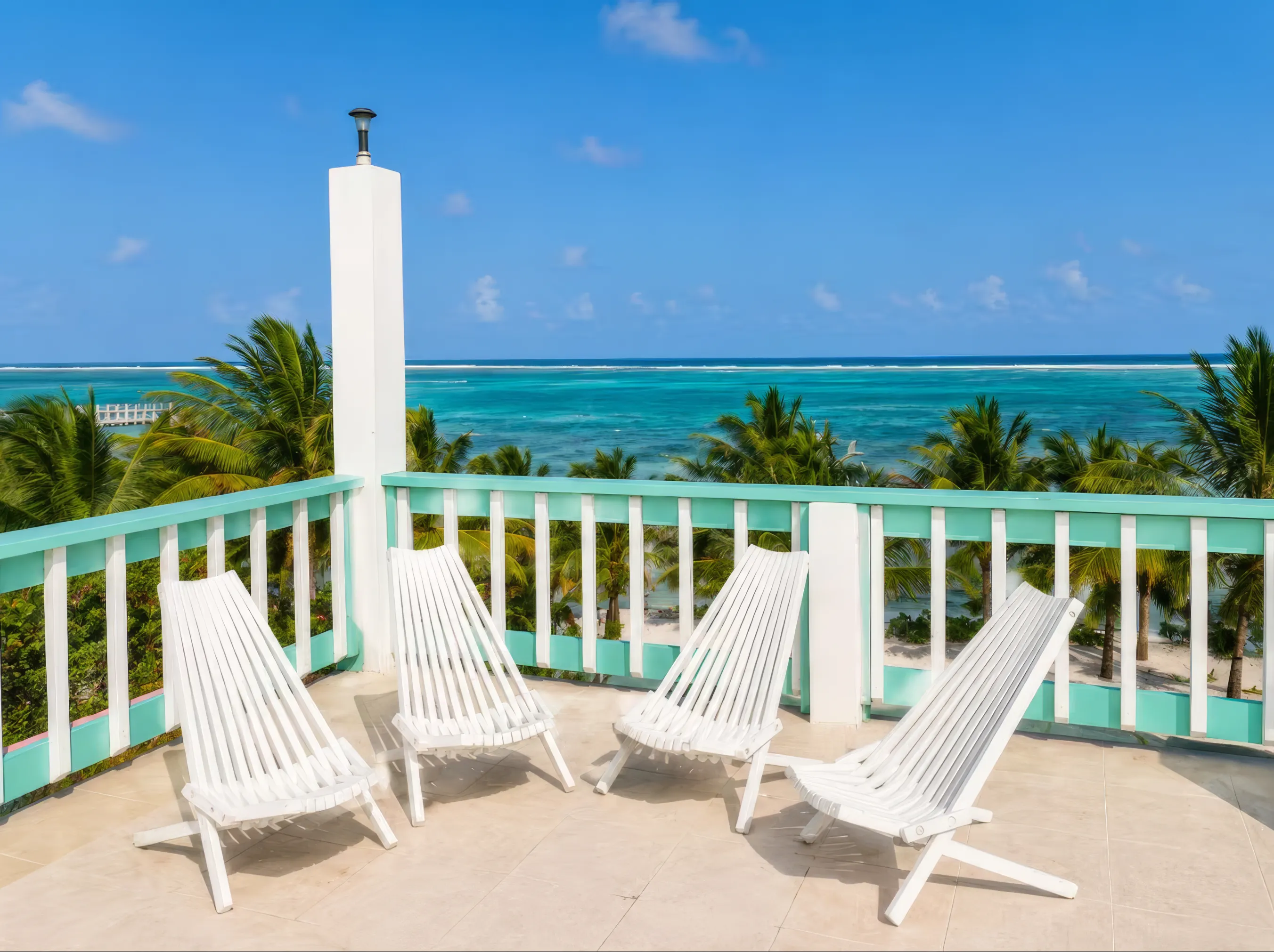 White wooden lounge chairs on the upper deck, with palms and the sea beyond the railing