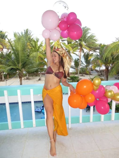 A guest holding a bunch of pink and orange balloons on the veranda
