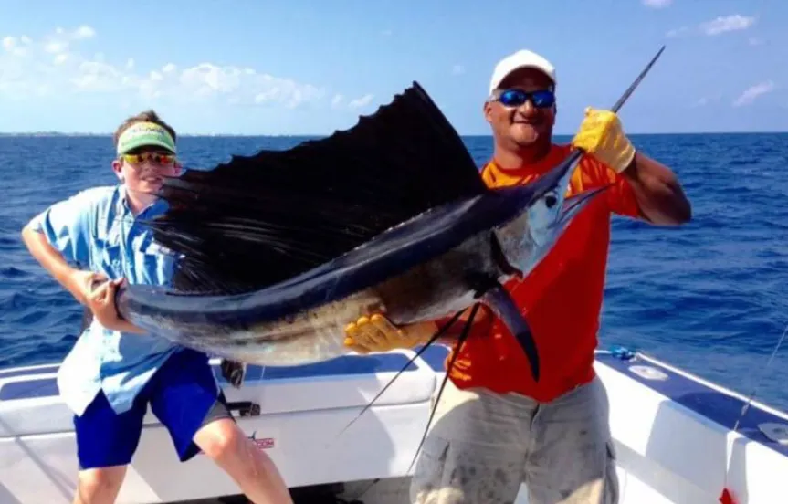 Two anglers on a boat holding up a large sailfish
