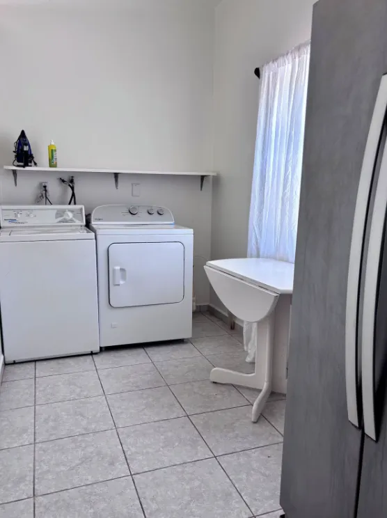A laundry room with a white washer and dryer beneath a shelf